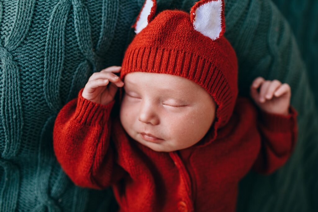 bébé dans barboteuse renard orange sur plaid vert