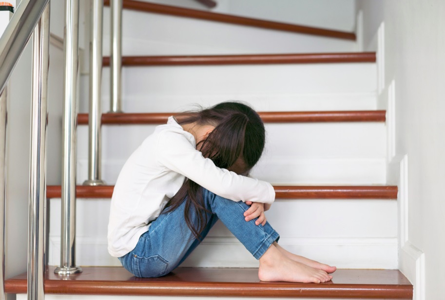 Une enfant recroquevillée dans les escaliers